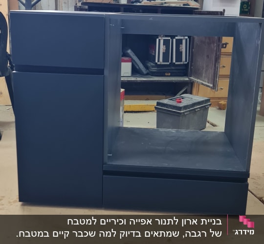 ארון מטבח בעבודת נגרות עם כלים ברקע בסדנה